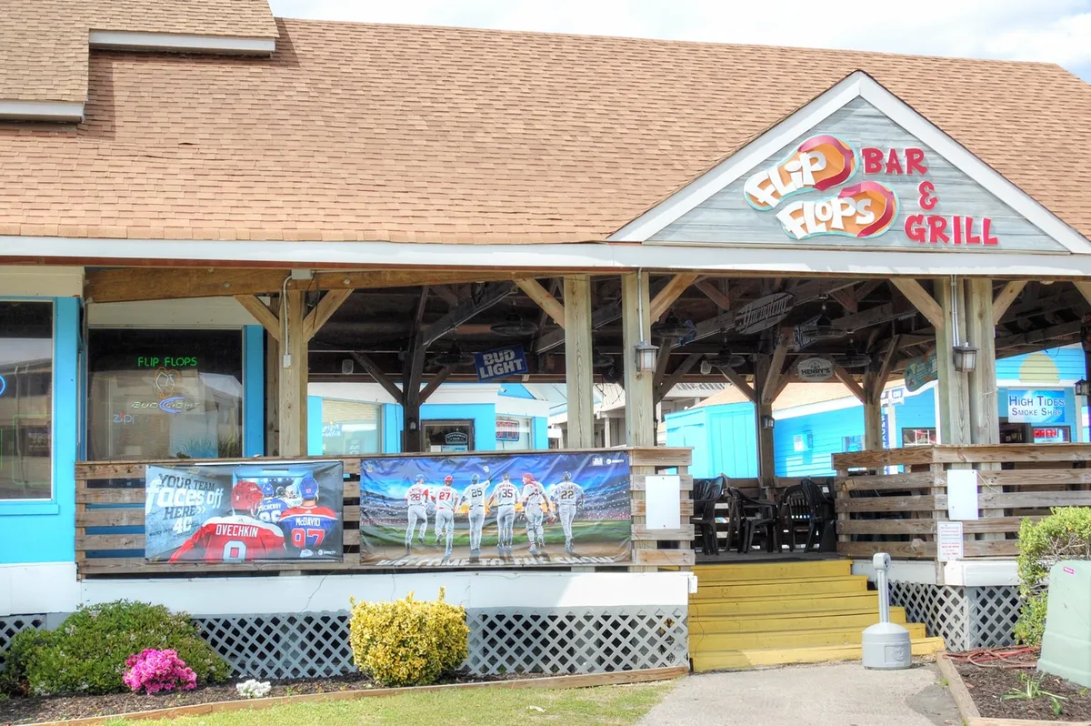 This exterior image features restaurant signage, sports-themed decorations, and an inviting outdoor seating area. The scene is lively yet relaxed, with visible cues that suggest a social and welcoming atmosphere for groups or couples.