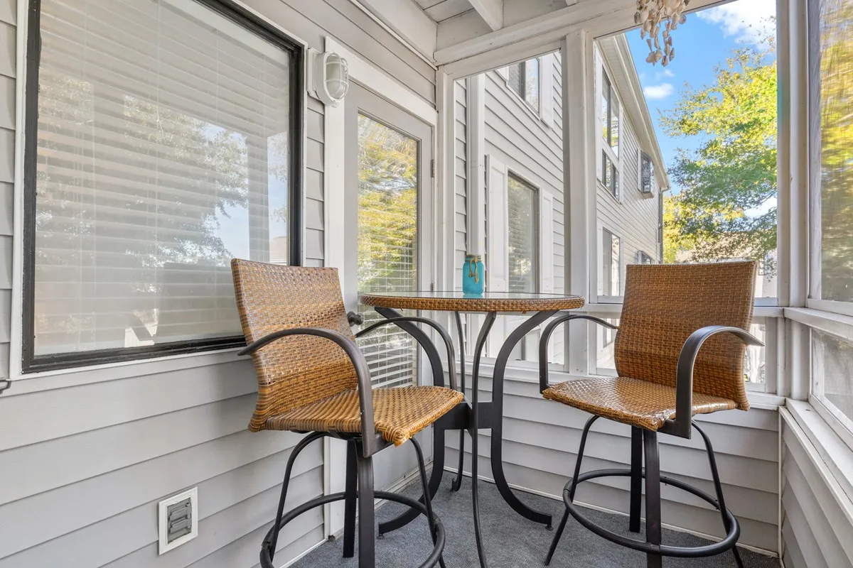 A cozy bar table with stool chairs is positioned next to large windows, inviting guests to enjoy their coffee or unwind with drinks while soaking in views and natural light. The relaxed scene hints at a direct connection to the balcony, perfect for sunrise rituals or sunset toasts.