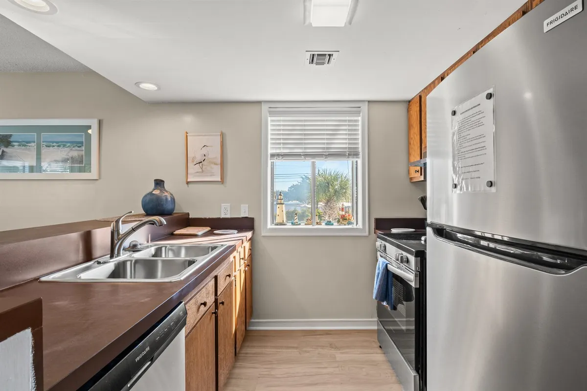 A well-lit view of the kitchen sink area, including a window with a view, modern stove and oven, and a large refrigerator. The space is open and welcoming, ideal for cooking and gathering, with thoughtful touches that support socializing and shared meals.